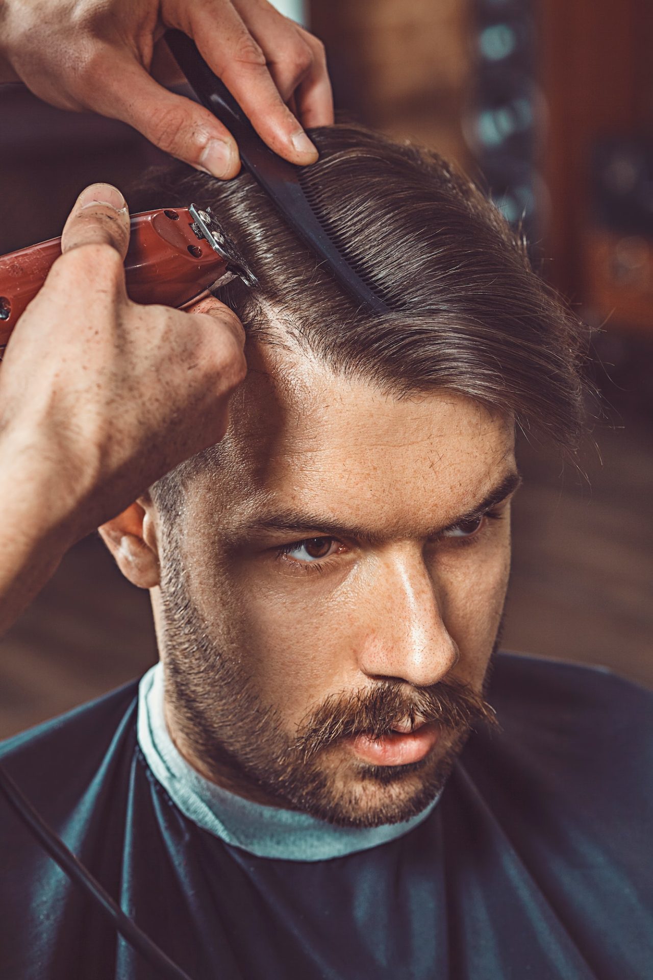 the-hands-of-young-barber-making-haircut-to-attractive-man-in-barbershop.jpg